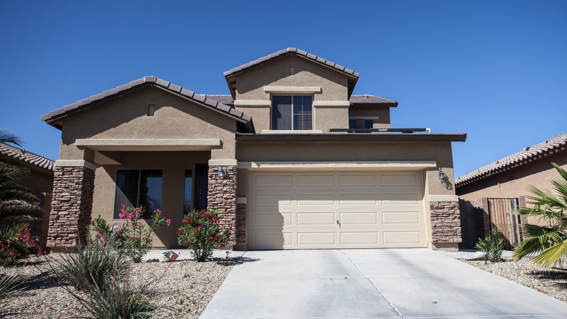Two-story suburban house with stone accents and two-car garage in desert landscape