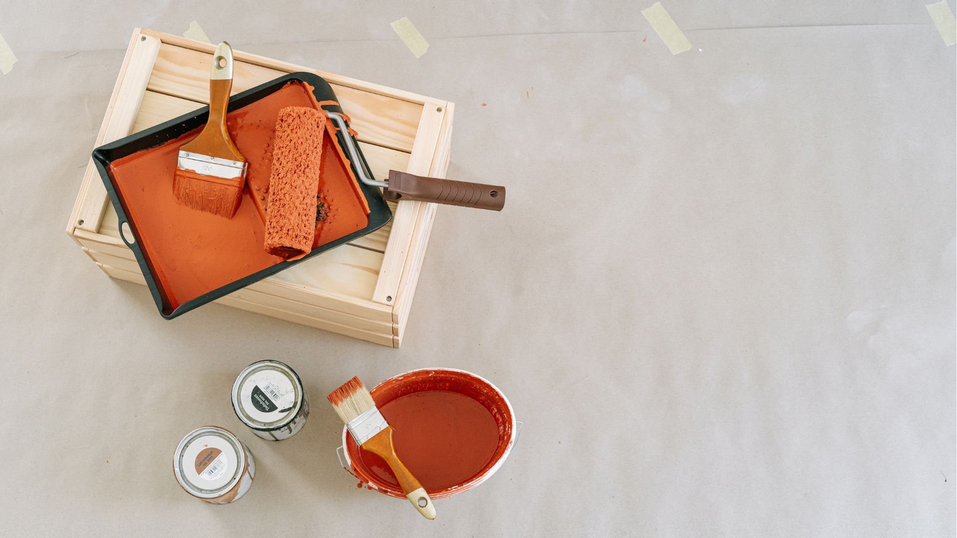 Orange paint, brushes, and paint tray on wooden box for home renovation