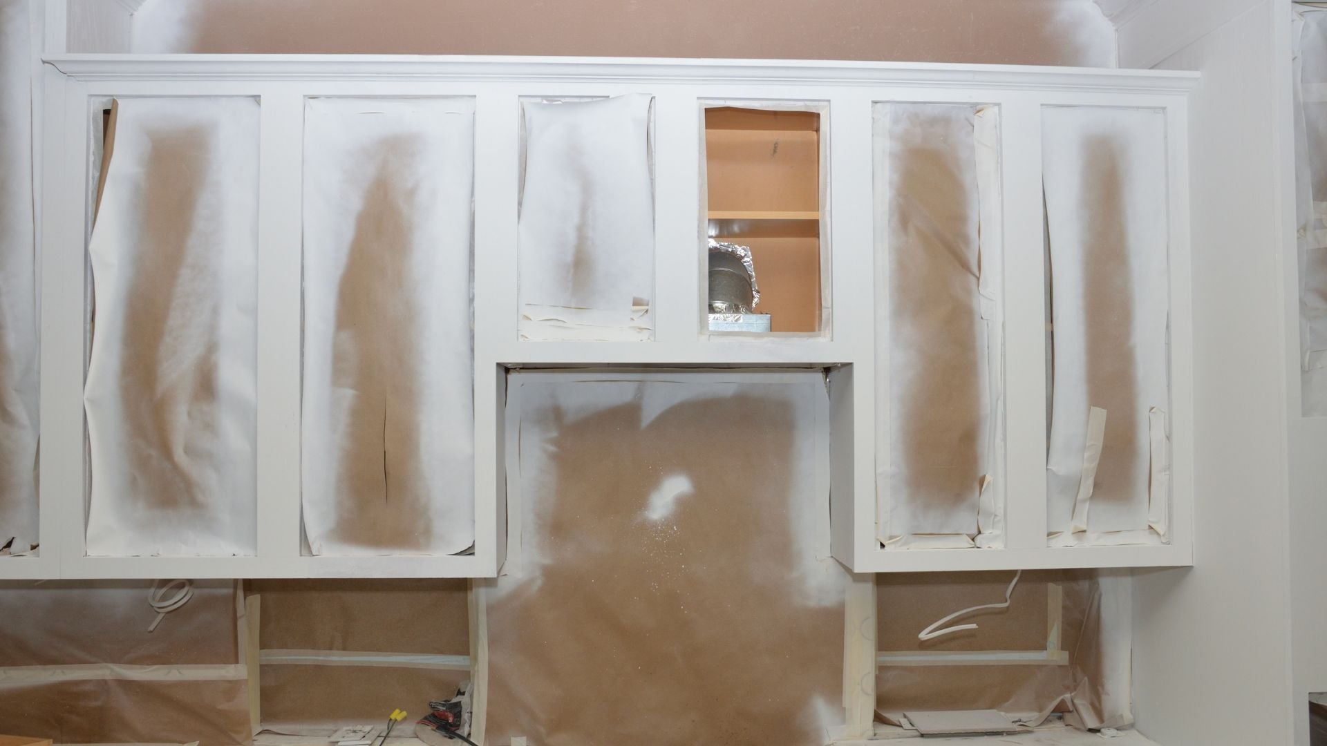 White kitchen cabinets during renovation with protective plastic covering