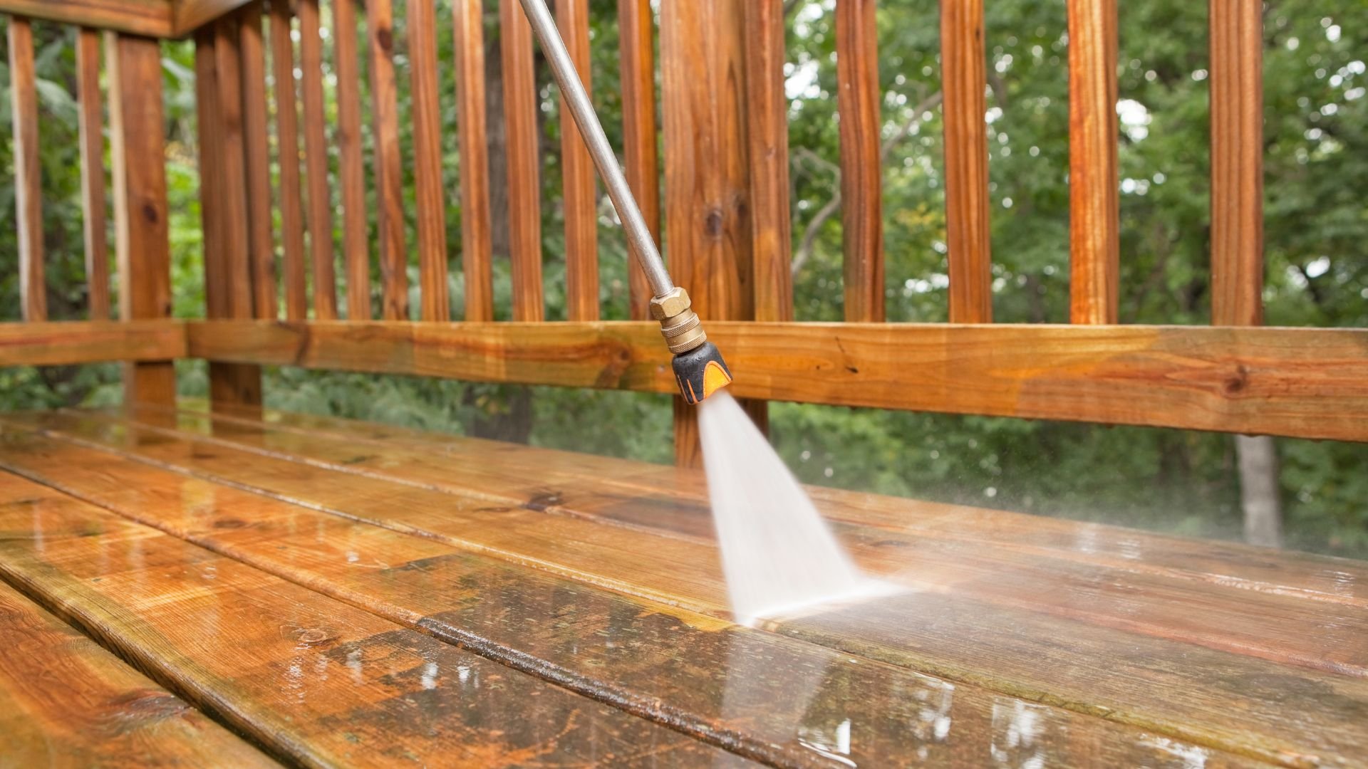 Pressure washer cleaning wooden deck with high-pressure water spray